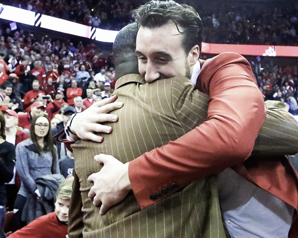 Frank Kaminsky and Howard Moore hugging in basketball stadium