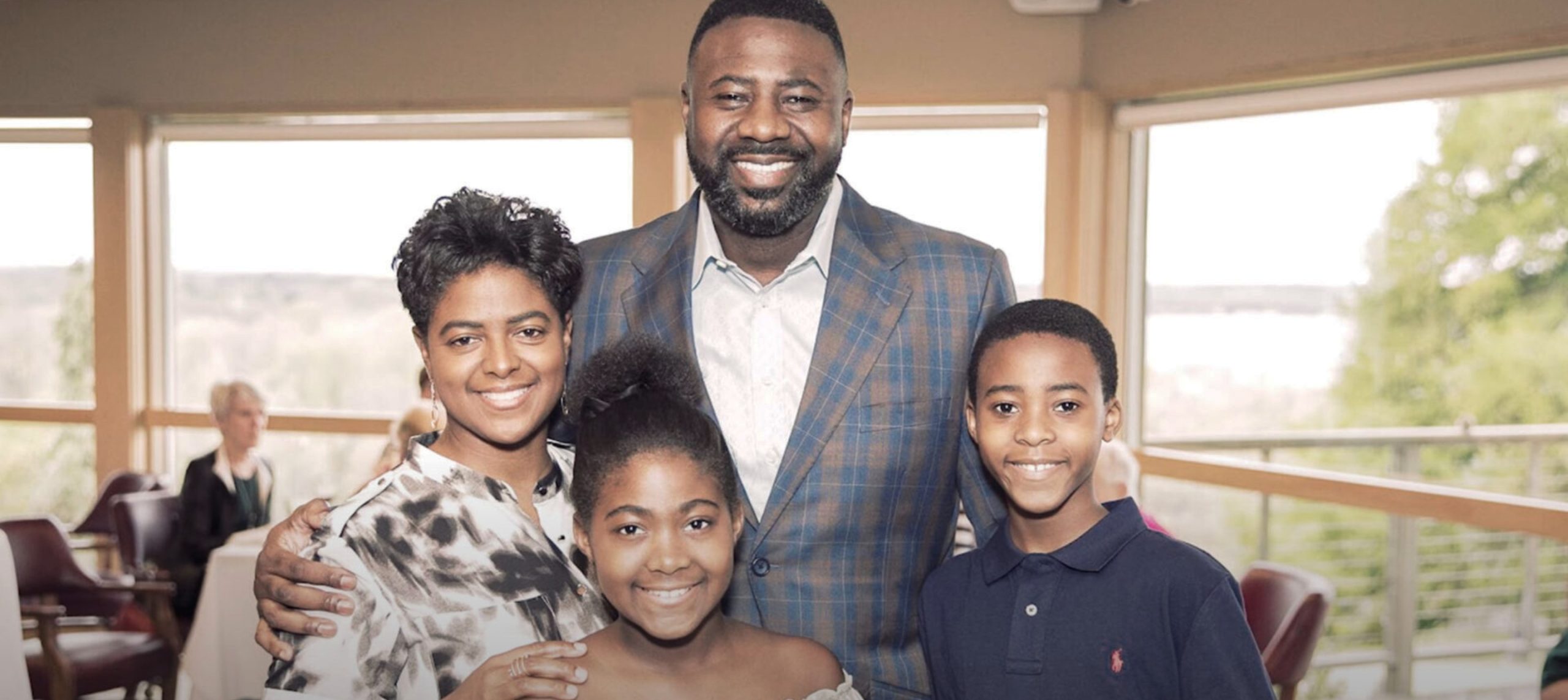 UW Wisconsin Basketball Coach Howard Moore with his family posing in front of a window